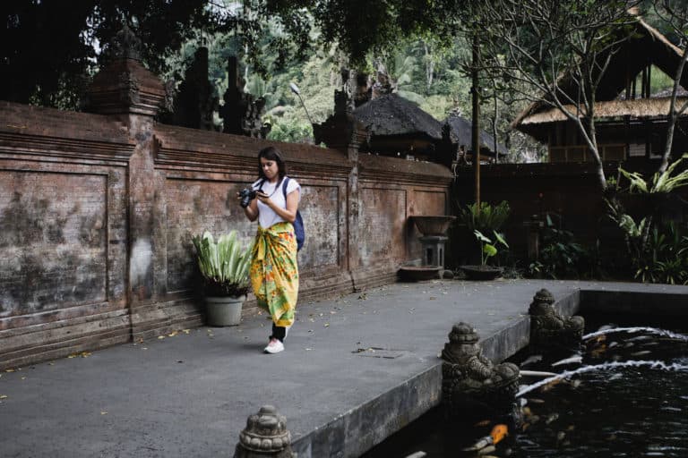 A woman in a yellow sarong at Tirta Empul Temple in Bali