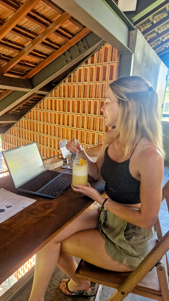 What To Wear In Bali - Outfit Ideas & Bali Packing Guide 10 Jodie coworking in Canggu with a juice in hand. She is wearing green lightweight shorts and a grey crop top.