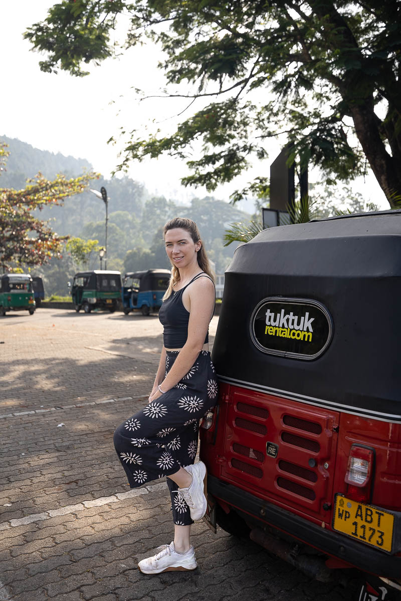 Renting A Tuk Tuk In Sri Lanka: My Experience & Must-Know Tips For Planning Your Tuk Tuk Trip 11 Jodie leaning against a red tuk tuk with TukTukRental.com branding on it