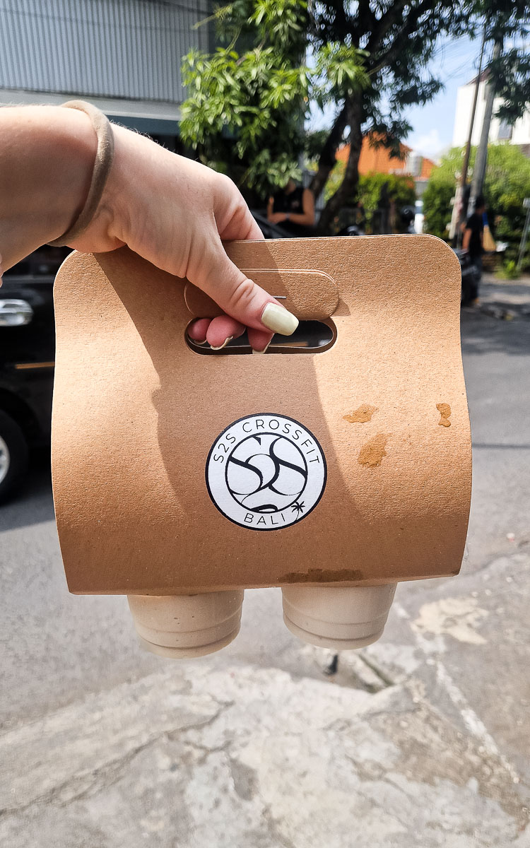 Vegan Canggu: A tried-and-tested guide to vegan cafes & restaurants in Bali's digital nomad hotspot 19 Jodie carrying two vegan protein smoothies in a cardboard drinks carrier. It has the S2S logo on it