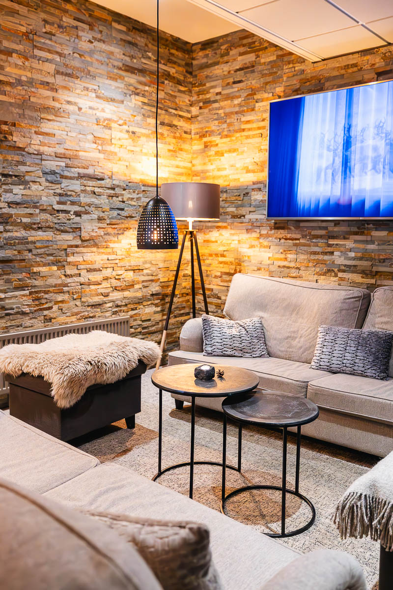 Kuopio in Winter: A Surprising Lapland Alternative in Finland's Lakeland Region 5 Lounge area in Lapland Hotels Kuopio in Finland. There are several sofas around two small tables with low hanging lamps, creating a cosy feel. Rugs and fluffy cushions on the sofas make it extra cosy.