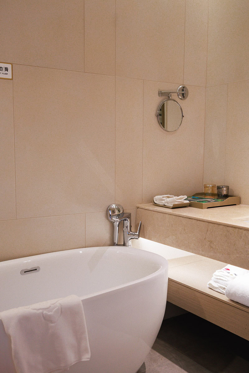 Bathroom with modern bathtub inside a room at Old Kapok Hotel in Daxin, Guangxi China